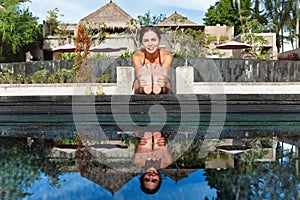 Active woman in bikini stretching at poolside to keep fit