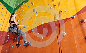 Active woman climbing up the wall in gym