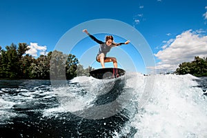 Active woman coolly balancing on surfboard on splashing wave photo