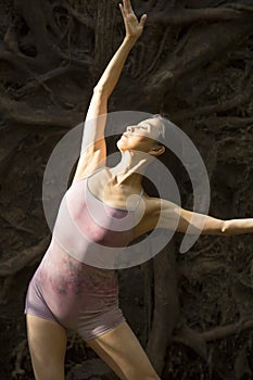 Active woman dancing with overturned tree roots in Manchester, Connecticut