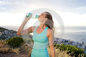 Active woman drinking from water bottle in front of the sea photo