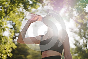Active woman drinking water after workout in nature