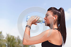 Active Woman With Earbuds Drinking Water