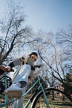 Active woman enjoying carefree bike ride in urban park on sunny day.