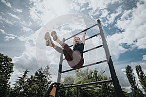 Active woman exercising on monkey bars at a park, showcasing fitness and strength