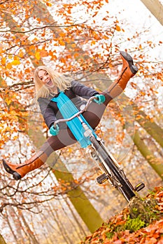 Active woman having fun riding bike in autumn park