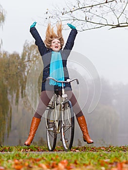 Active woman having fun riding bike in autumn park