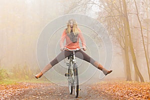 Active woman having fun riding bike in autumn park