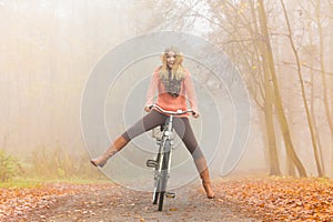 Active woman having fun riding bike in autumn park