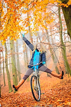 Active woman having fun riding bike in autumn park