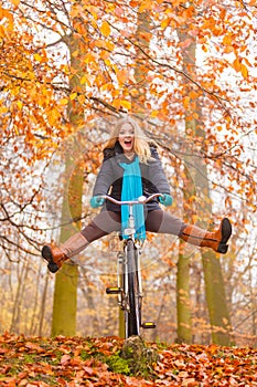 Active woman having fun riding bike in autumn park