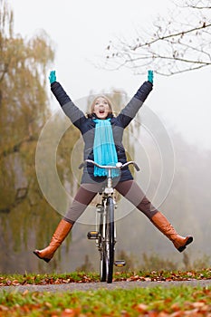 Active woman having fun riding bike in autumn park