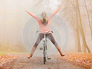 Active woman having fun riding bike in autumn park