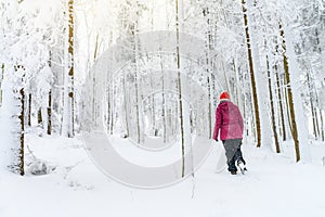 Active woman hiking in white winter snowy forest