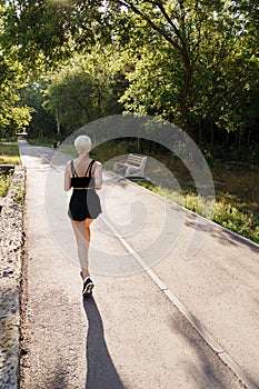 Active woman jogging on a sunny park pathway