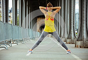 Active woman on Pont de Bir-Hakeim bridge in Paris stretching