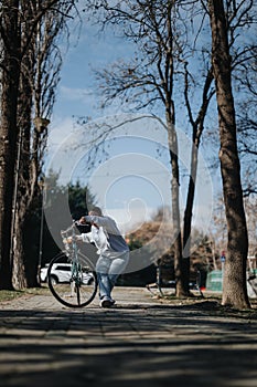 Active woman pushing her bicycle along a tree-lined path in the park.