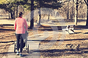 Active woman pushing a stroller through a park