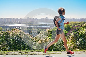 Active woman runner run commutes to work with backpack, city morning run commuting and healthy lifestyle concept, skyline of Kyiv