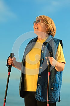 Active woman senior nordic walking on a beach