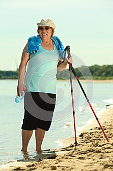 Active woman senior nordic walking on a beach