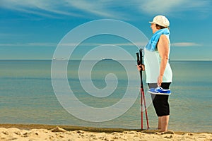 Active woman senior nordic walking on a beach