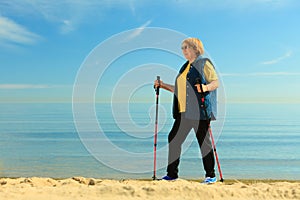 Active woman senior nordic walking on a beach