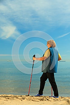 Active woman senior nordic walking on a beach