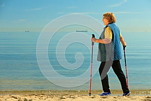 Active woman senior nordic walking on a beach