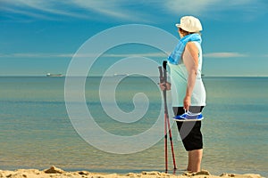 Active woman senior nordic walking on a beach