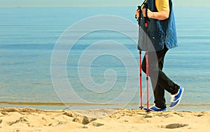 Active woman senior nordic walking on a beach. legs