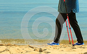 Active woman senior nordic walking on a beach. legs