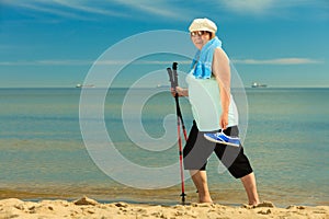 Active woman senior nordic walking on a beach