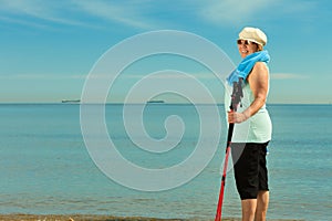 Active woman senior nordic walking on a beach