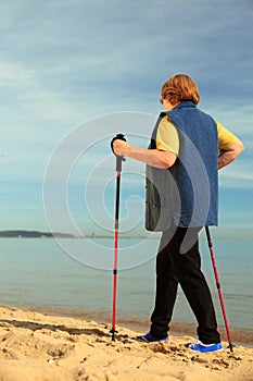 Active woman senior nordic walking on a beach