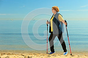 Active woman senior nordic walking on a beach