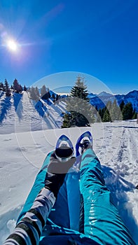 Active woman in snow shoes having a tea break with scenic view on snow capped mountain peaks of Karawanks in Carinthia, Austria.