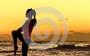 Active woman in sport clothes on seashore stretching