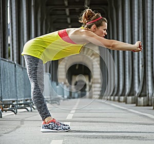 Active woman stretching on Pont de Bir-Hakeim bridge in Paris