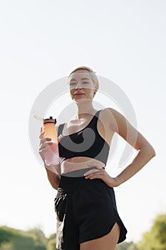 Active woman taking a break with water bottle outdoors