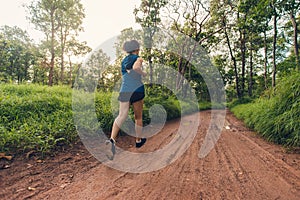 Active woman trail runner running in the forest in the morning