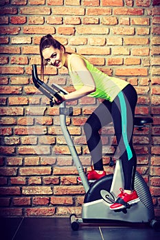 Active woman using exercise bike at the gym.