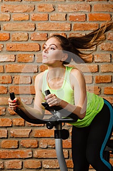 Active woman using exercise bike at the gym.