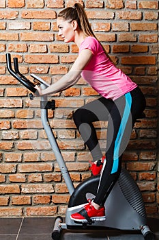 Active woman using exercise bike at the gym.