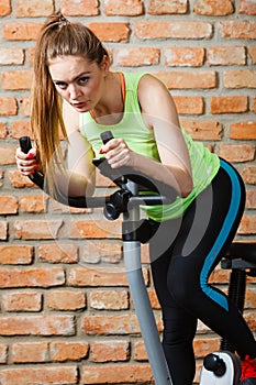 Active woman using exercise bike at the gym.