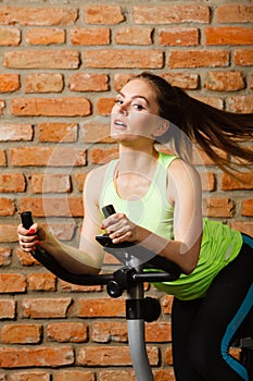 Active woman using exercise bike at the gym.