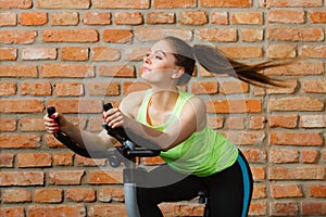 Active woman using exercise bike at the gym.