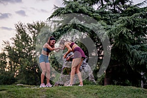 Active Women Enjoying Fun Moments Splashing Water in Park After Strenuous Training