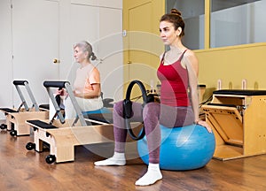 Active women perform exercises with fitness balls and Pilates rings