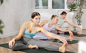 Active women perform a stretching exercise in a pose Janu Shirshasana